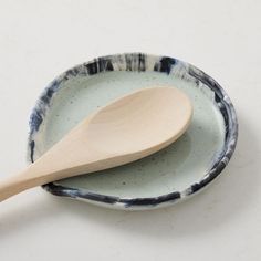 a wooden spoon sitting on top of a blue and white bowl with the words west elm written below it