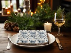 a place setting on a table with candles and pine branches in the background, along with a glass of white wine