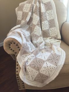 a white crocheted blanket sitting on top of a couch next to a window