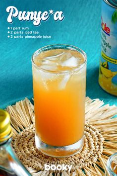 an orange drink sitting on top of a straw mat next to a can of juice