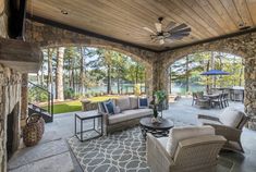 an outdoor living room with stone walls and ceiling fans, couches, tables and chairs