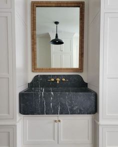 a bathroom sink sitting under a mirror in front of a wall mounted faucet