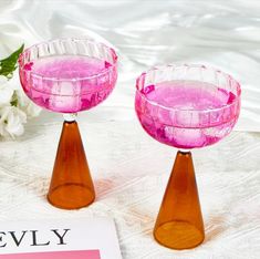 two pink candlesticks sitting on top of a table next to a white flower