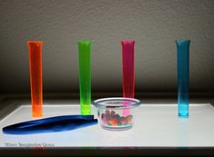 four different colored vases sitting next to each other on a white counter top with candy in them