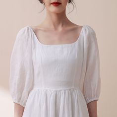 a woman wearing a white dress with puffy sleeves and a red lipstick on her lips