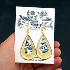 "Lavender Teardrop Earrings These earrings feature real pressed lavender buds, encased in resin, in a bright brass teardrop shaped setting. Attached to matching hooks and each measures 1.75\" x 1\"" Nature-inspired Teardrop Earrings With Pressed Flowers, Gold Teardrop Jewelry With Pressed Flowers, Resin Teardrop Earrings For Gifts, Gold Teardrop Birth Flower Earrings, Gift Brass Teardrop Drop Earrings, Pressed Lavender, Flower In Resin, Drop Gold Earrings, Megan Brown