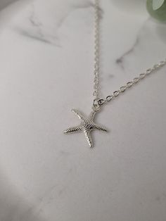 Silver plated starfish charm attached to an 18inch silver plated sparkle chain necklace with lobster claw closure. The charm is attached to the necklace via a silver plated jump ring. The charm measures 1.9cm long x 1.9cm wide. The necklace measures 18inches. This super cute starfish necklace is a great reminder of times spent near the seaside. The necklace will come gift wrapped in tissue paper and an organza bag. Please note that although I have endeavour to show of my pieces in the best, natural light, the colour may vary slightly due to screen resolution/brightness. However, if you have any questions then please feel free to message me. Silver Star-shaped Adjustable Necklace, Adjustable Silver Star Necklace, Dainty Starfish Necklace For Beach, Ocean-inspired Pendant Charm Necklace As Gift, Starfish Charm Pendant Jewelry Gift, Starfish Charm Pendant Jewelry For Gift, Starfish Nickel-free Necklace As Gift, Nickel-free Starfish Necklace For Gift, Ocean-inspired Jewelry With Starfish Charm For Gift