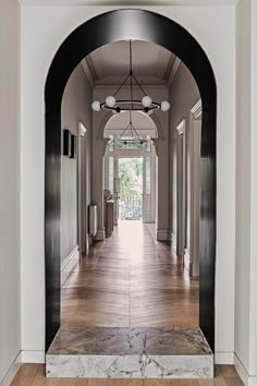 an arched doorway leading to a hallway with marble floors and white walls on either side