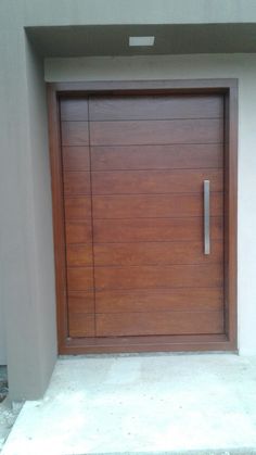 a large wooden door in front of a white wall