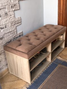 a brown bench with shoes on it in front of a brick wall and blue rug