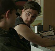 a man sitting at a counter with his hand on the back of another man's shoulder