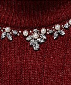 a red sweater with pearls and crystals on the collarline is seen in this close up photo