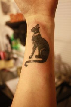 a black cat tattoo on the wrist is shown in front of a woman's hand