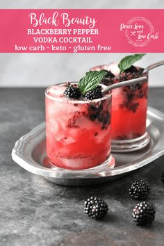 two glasses filled with blackberries on top of a metal tray next to some berries