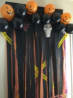 halloween decorations are hanging on the wall with black and orange balloons in front of them