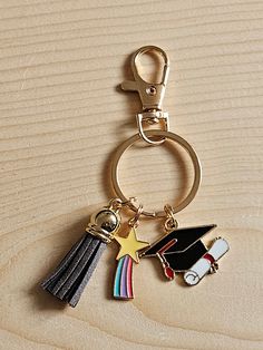 a keychain with a graduation cap, star and tassel on it sitting on a wooden surface