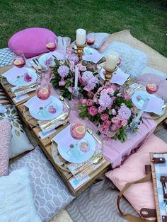 a table is set with pink and gold plates, napkins, flowers and candles