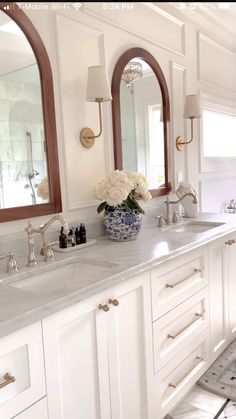 a white bathroom with double sinks and mirrors