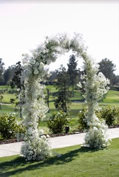 an outdoor wedding ceremony with white flowers and greenery on the grass, in front of a golf course