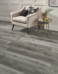 a living room with grey wood flooring and a white chair next to a coffee table