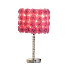 a red rose lamp on a metal stand with a white background and light reflecting off it's sides