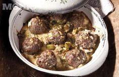 a white bowl filled with meatballs covered in gravy