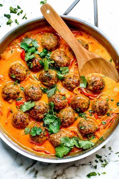 meatballs with tomato sauce and parsley in a skillet on a marble counter