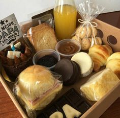 an open box filled with pastries and desserts next to a glass of orange juice