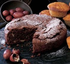 a chocolate cake with one slice cut out and other pastries on the table next to it