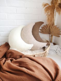 four different colors of blankets in a basket on a bed with a brick wall behind them