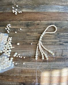 beads and thread are laid out on a wooden surface to spell out the word love