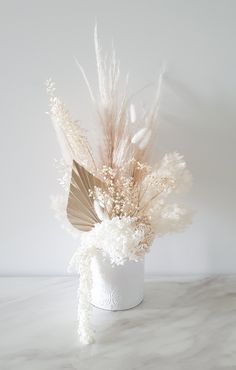 a white vase with flowers and feathers in it