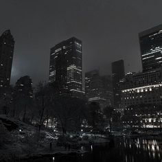 black and white photograph of city at night with lights reflecting in the water's surface