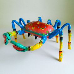 a colorful crab made out of plasticine on a white surface with two legs and feet