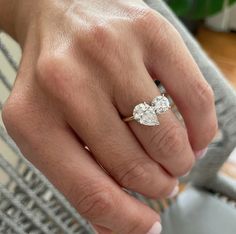 a close up of a person's hand wearing a ring with two diamonds on it