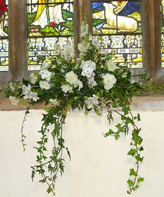 white flowers and greenery in front of stained glass windows