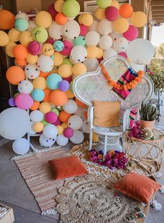 a room filled with lots of balloons on the wall next to a wicker chair