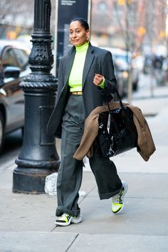 a woman is walking down the street with her hand in her pocket and holding a shopping bag