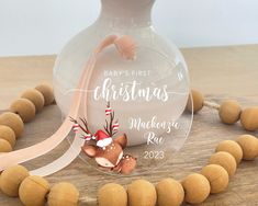 a baby's first christmas ornament in a glass bottle on a wooden bead necklace