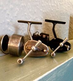 two metal fishing rods and reels on a shelf