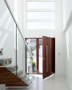 an open door leading up to a white staircase with glass balconies on both sides