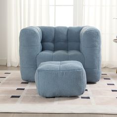 a blue chair and ottoman sitting on top of a rug in front of a window