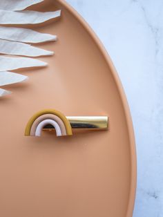 a piece of white paper on top of a pink plate with a gold handle and ring