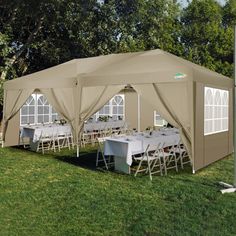 a large tent with tables and chairs set up in the grass