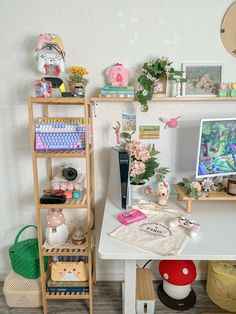 a white desk topped with a computer monitor next to a shelf filled with books and other items