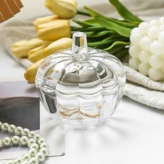 a glass jar sitting on top of a table next to flowers and pearls around it