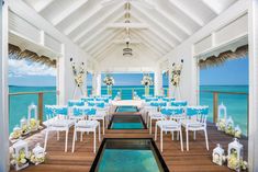 an outdoor dining area with tables and chairs on the water's edge, overlooking the ocean