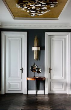 a room with two white doors and a table in the middle, on top of a hard wood floor