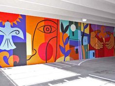 an empty parking garage with colorful paintings on the wall