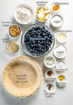 ingredients for blueberry pie laid out in bowls on a white surface with the words blueberries written below